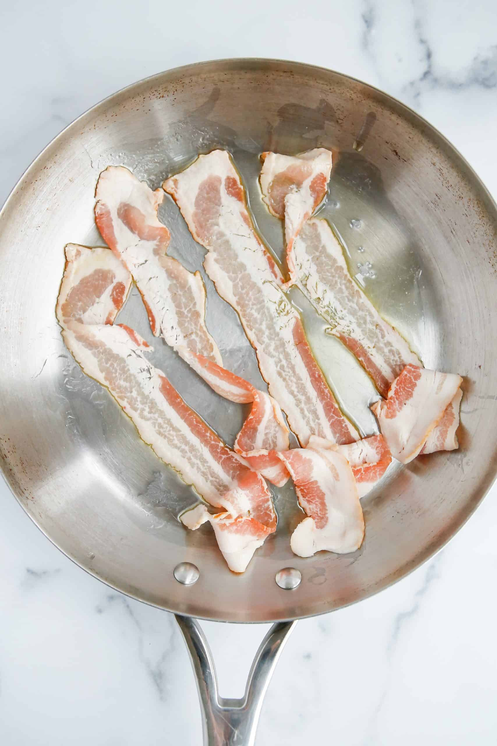 four bacon strips shown in a skillet. 