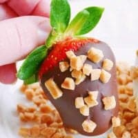 Hand holding one Chocolate Covered Strawberry thumbnail image