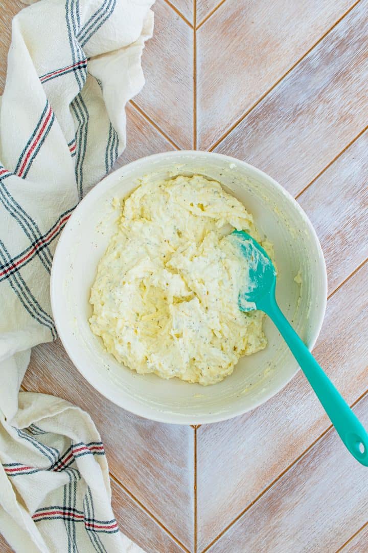 Mixed up ricotta filling in a white bowl with a blue spatula.