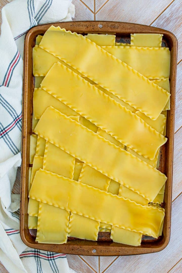 Cooked lasagna noodles in a criss cross pattern on baking sheet.