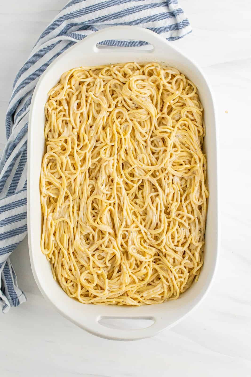 Alfredo covered spaghetti noodles in a prepared 9x13 baking dish.