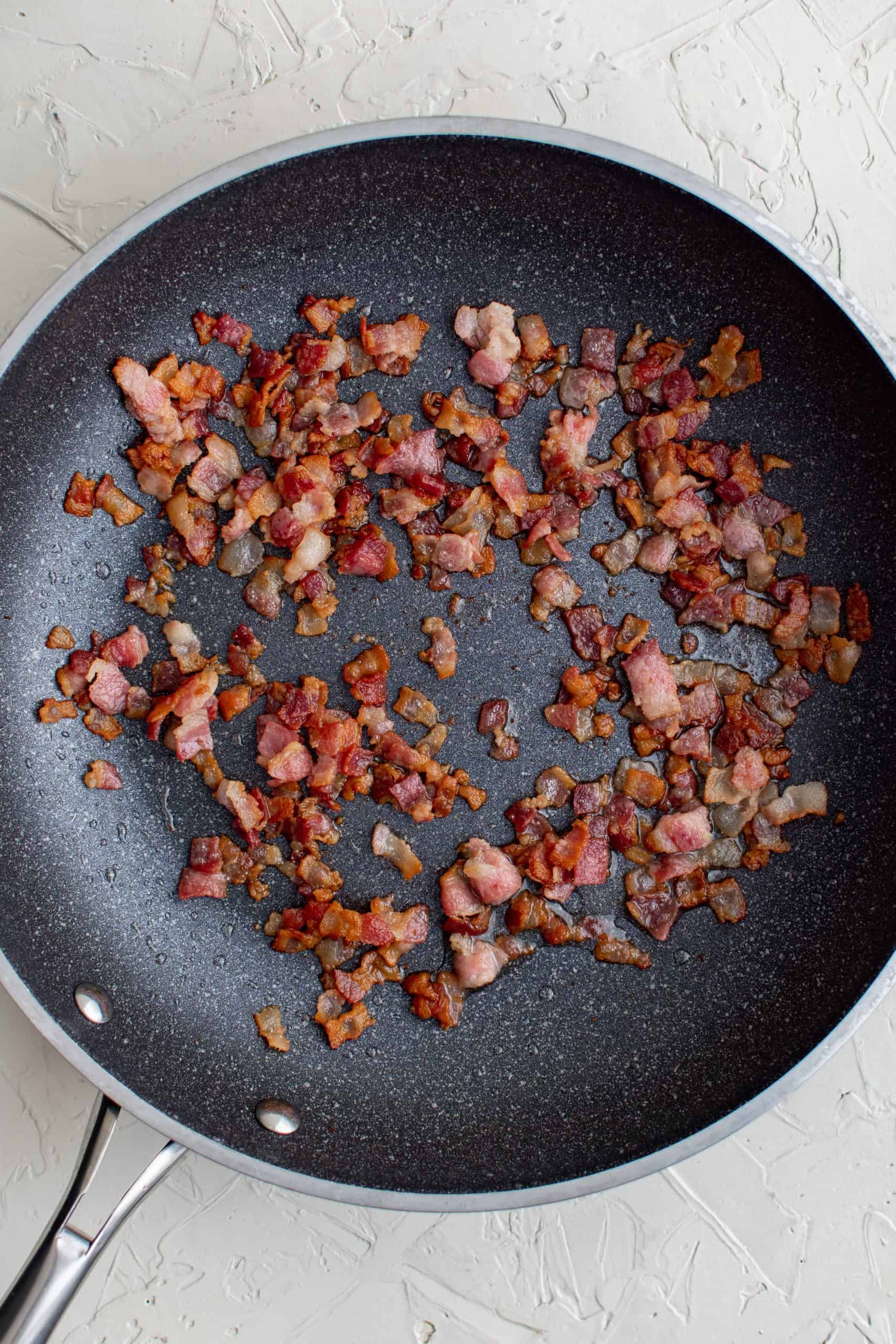 Cooked and crumbled bacon in a skillet. 