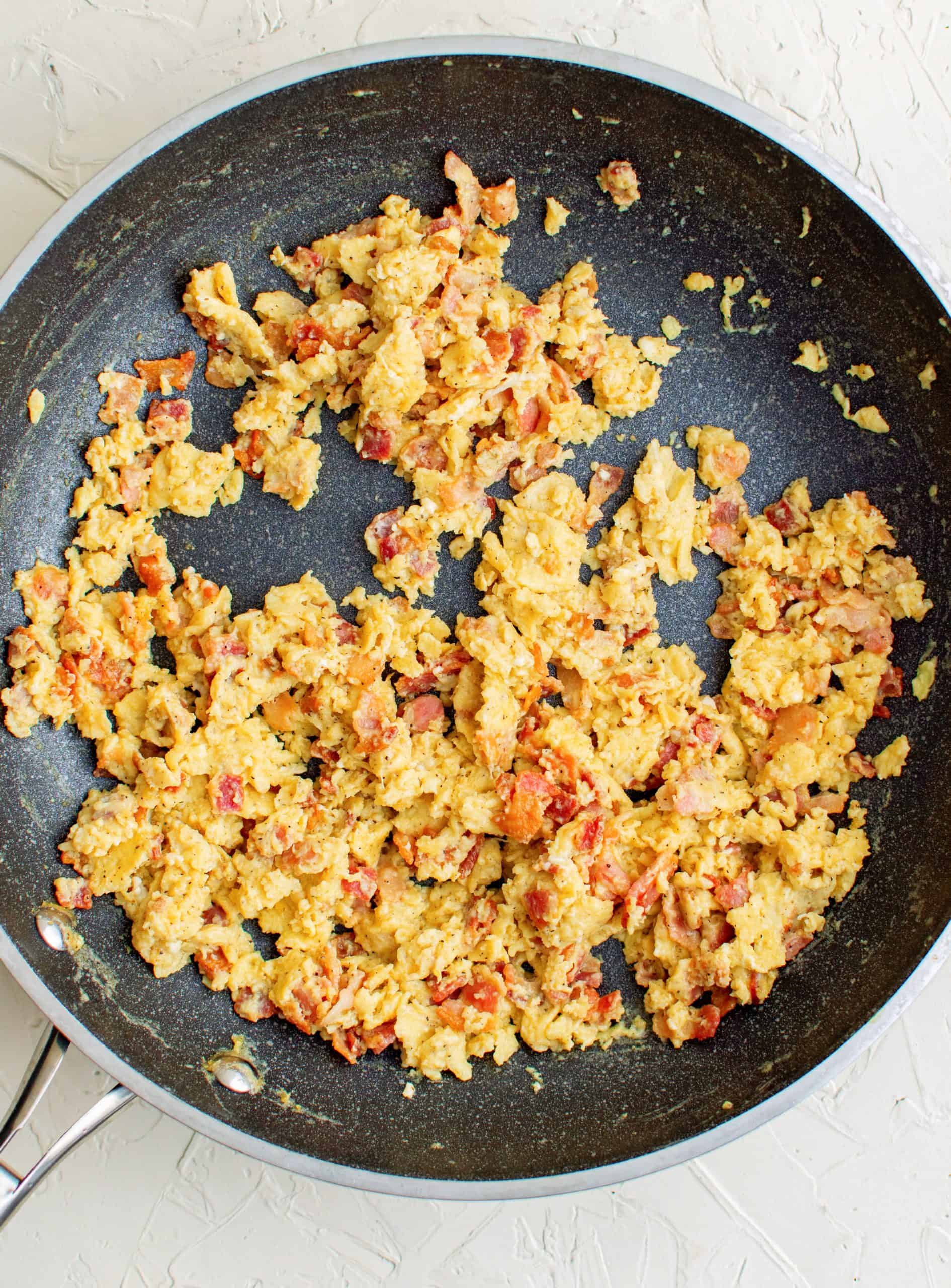 Bacon and eggs cooked in pan.