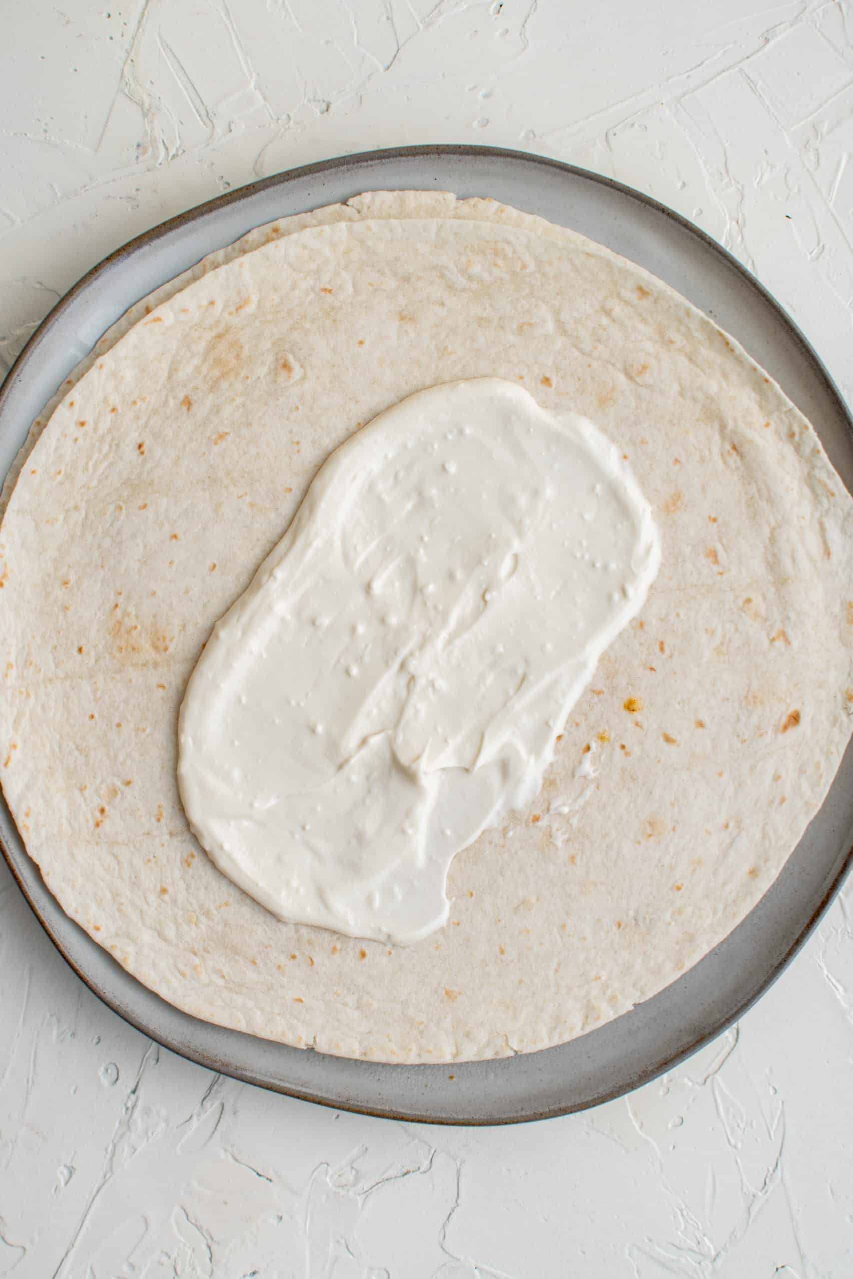 Sauce spread in center of one tortilla.