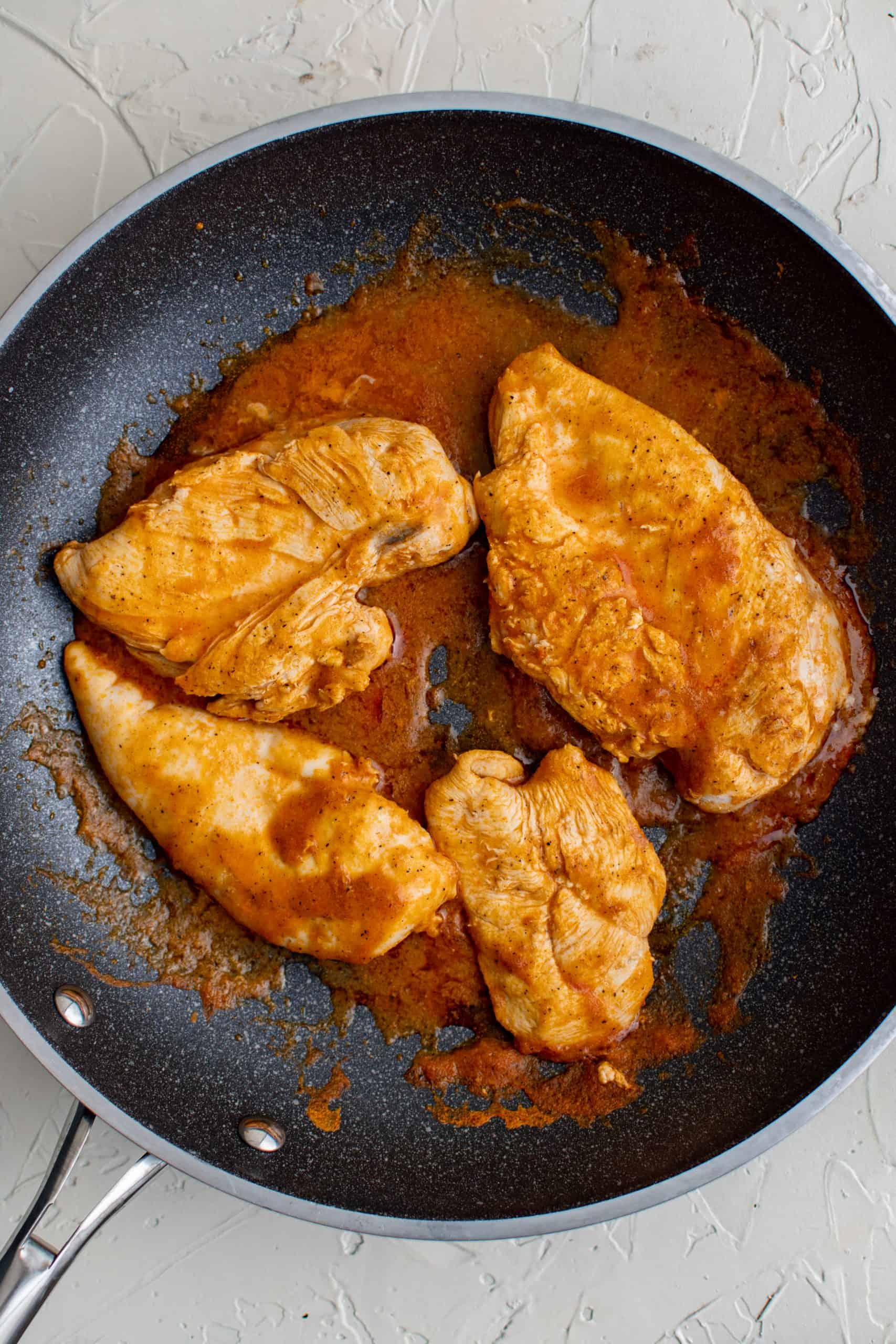 seasoned chicken breasts cooking in a skillet.