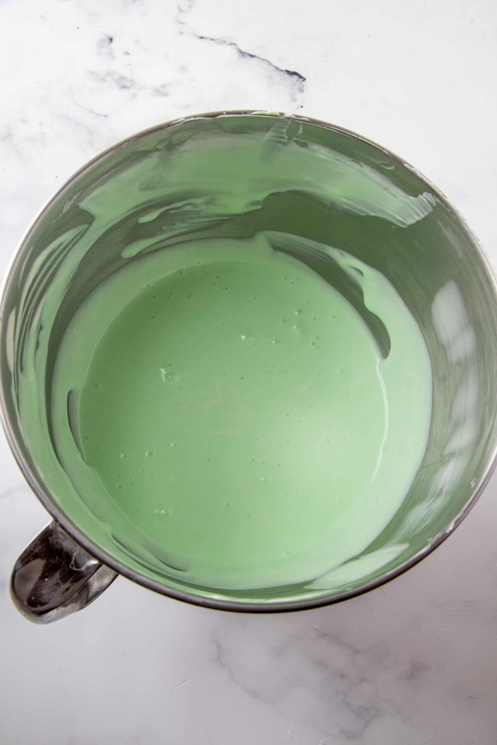Green cheesecake batter mixture in the bowl of a stand mixer.
