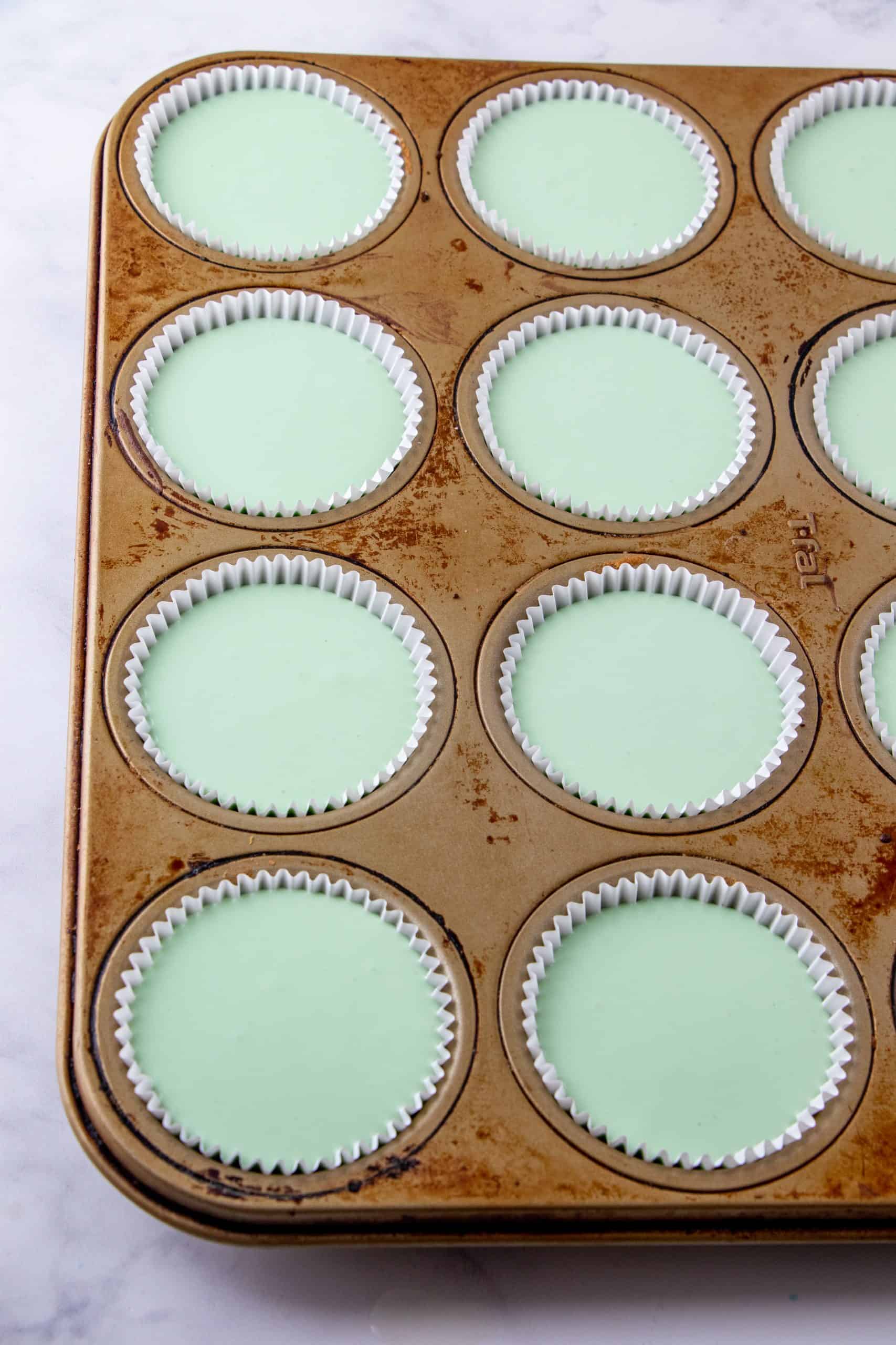Cheesecake batter mixture in paper liners in a muffin tin.