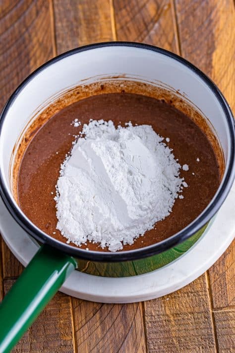powdered sugar added to butter and cocoa powder in a saucepan.