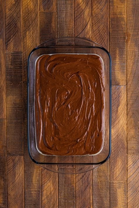 chocolate cake batter shown in a glass rectangle baking dish.