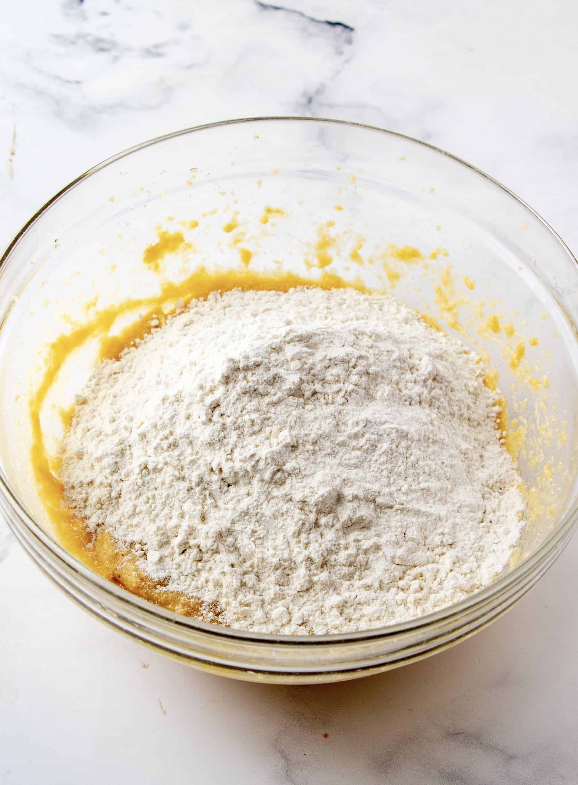 Flour adding egg and butter mixture in a bowl.
