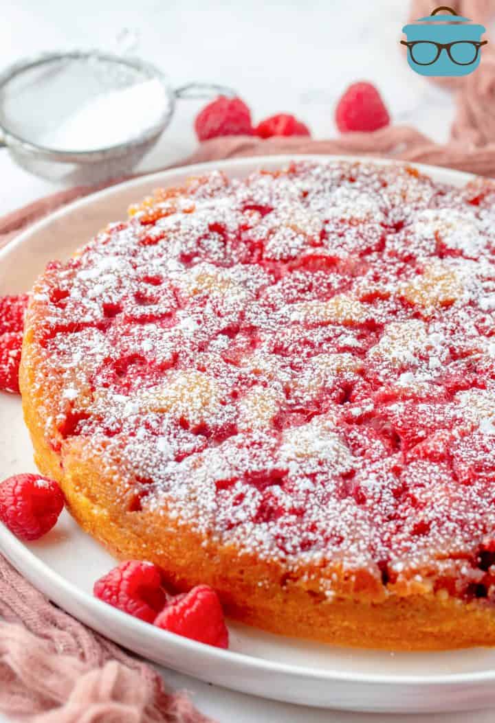 Upside Down Raspberry Cake on white platter topped with powdered sugar