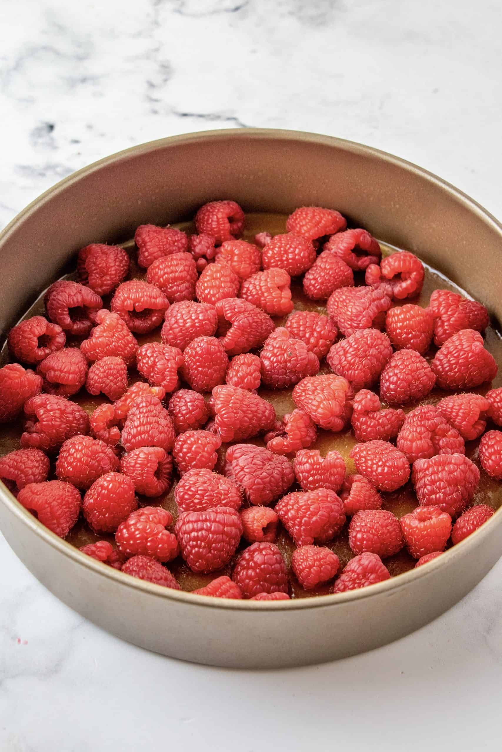 Raspberries on top of brown sugar mixture in pan.