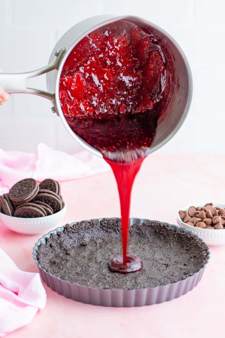 Raspberry mixture being poured over crust