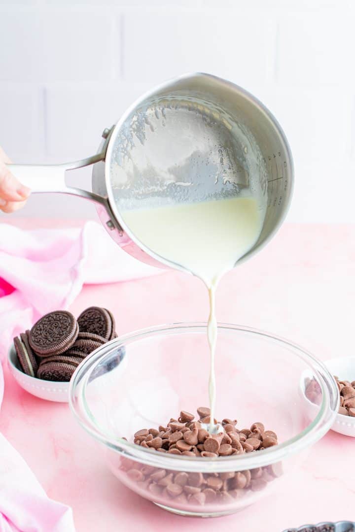 Heavy cream being poured over chocolate chips in bowl