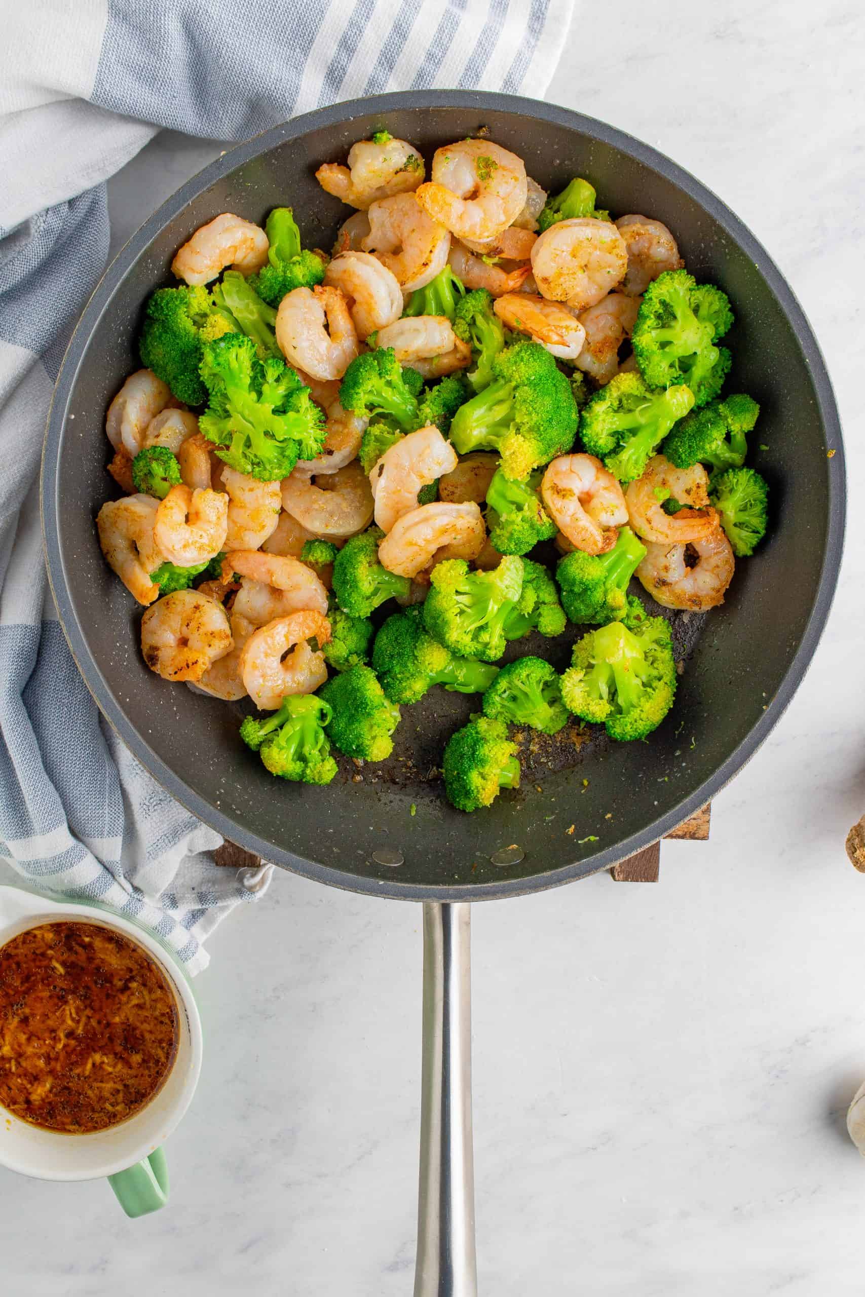 partially cooked Broccoli and shrimp in a skillet