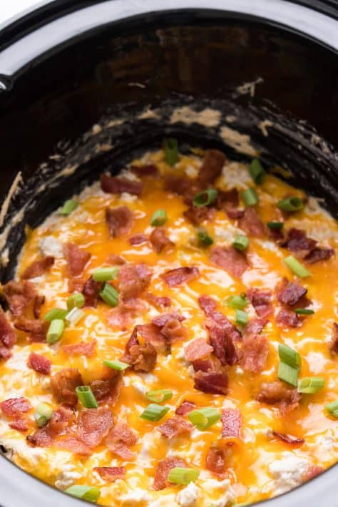 Melted cheese with bacon and green onions in crock pot on top of chicken