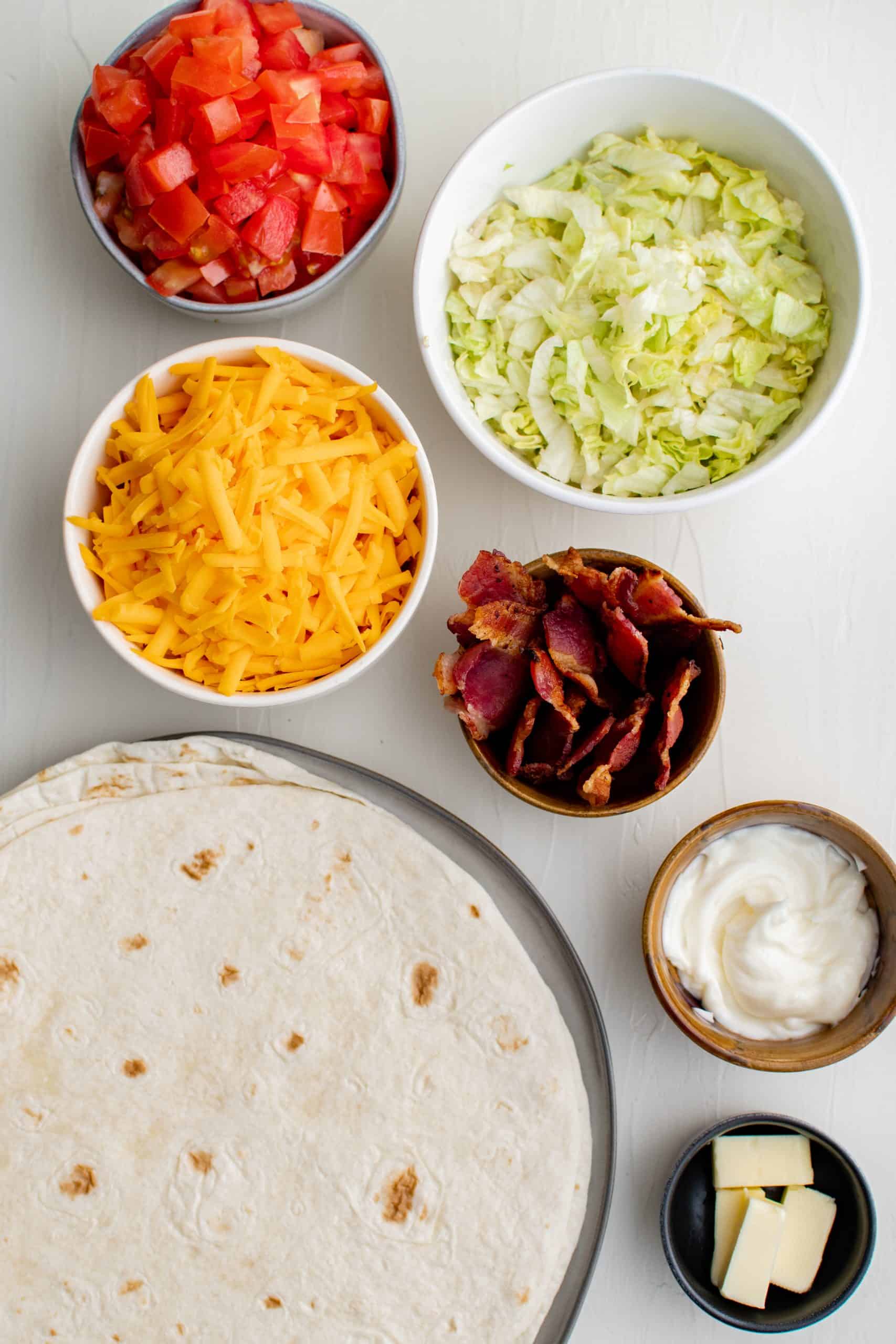 diced tomatoes, shredded cheddar cheese, shredded lettuce, cooked bacon and flour tortillas.