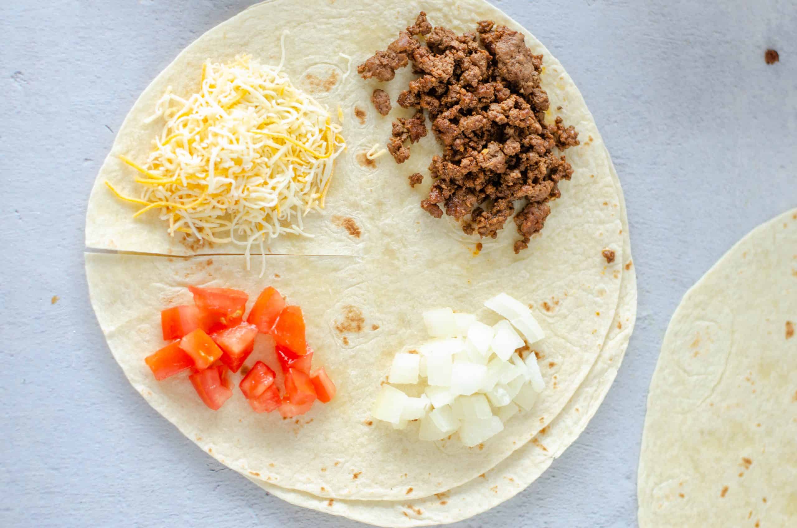Hamburger cheese, tomatoes and onions on each quarter of quesadilla