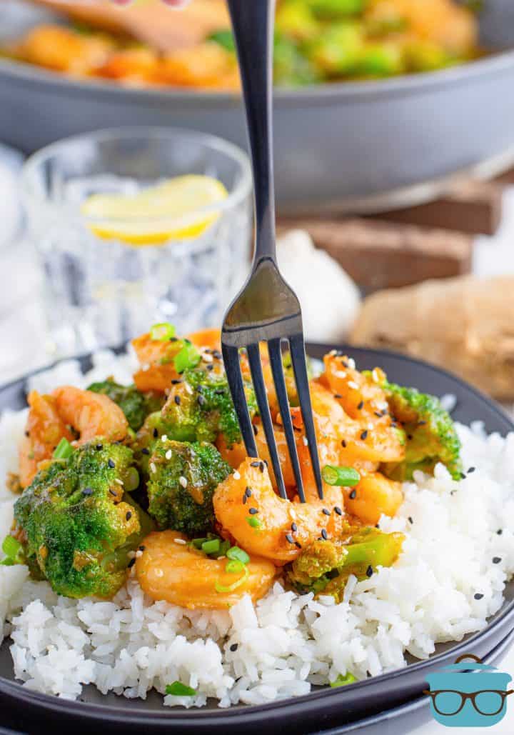 Shrimp and Broccoli over rice with fork poking into piece of shrimp