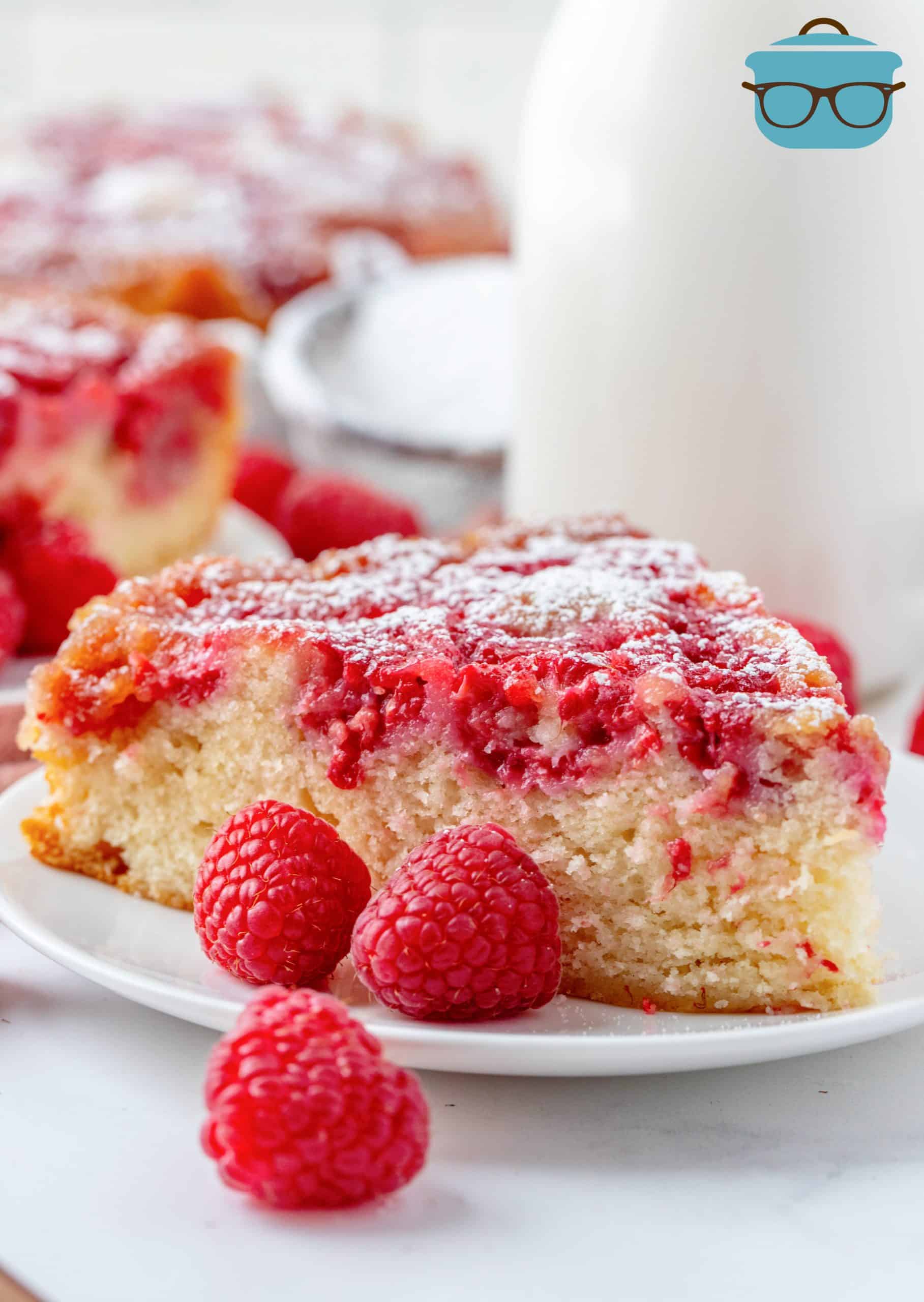 Slice of Raspberry Upside Down Cake on white plate with raspberries