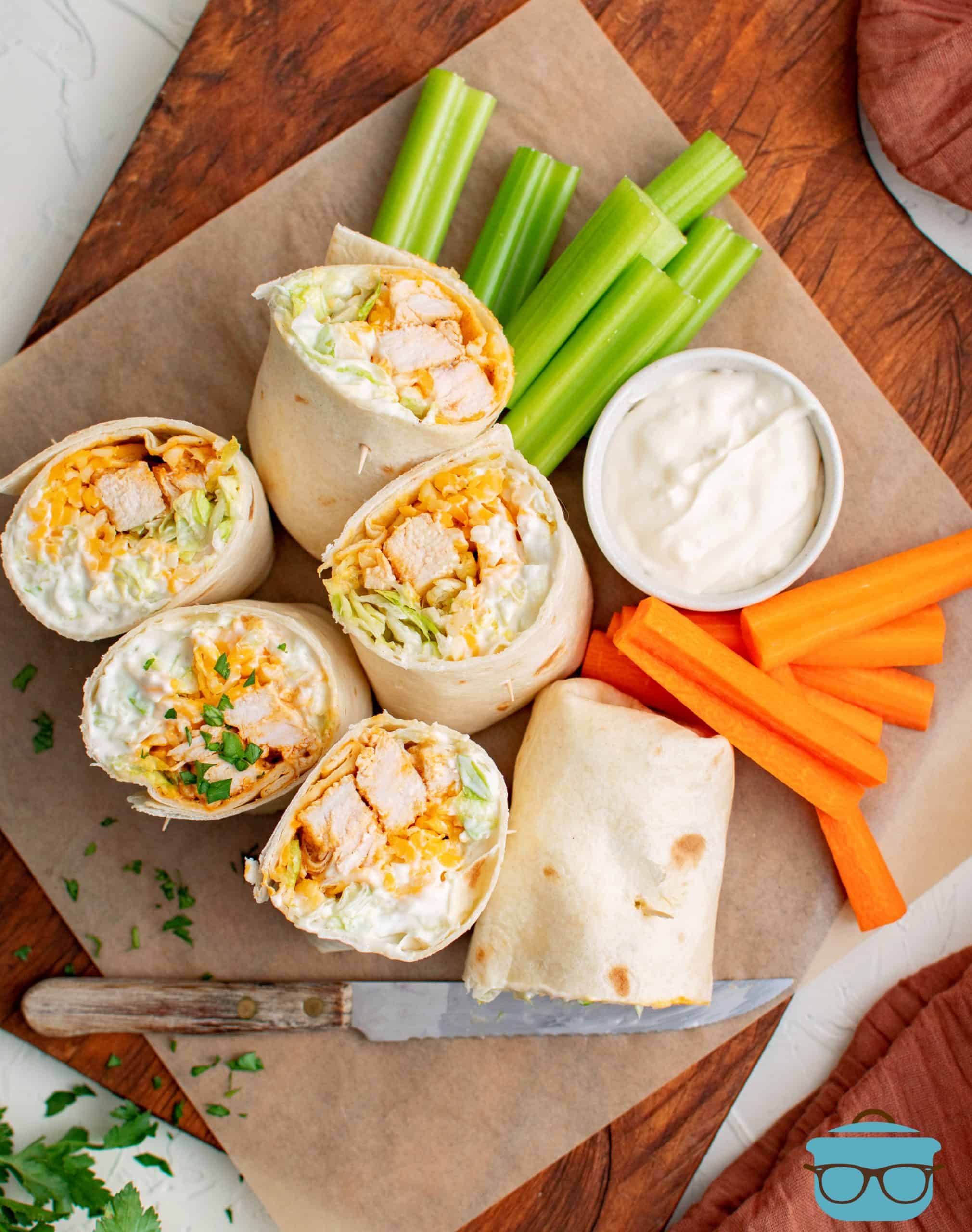 Overhead photo of cup open Buffalo Chicken Wraps with dipping sauce, celery and carrot sticks.