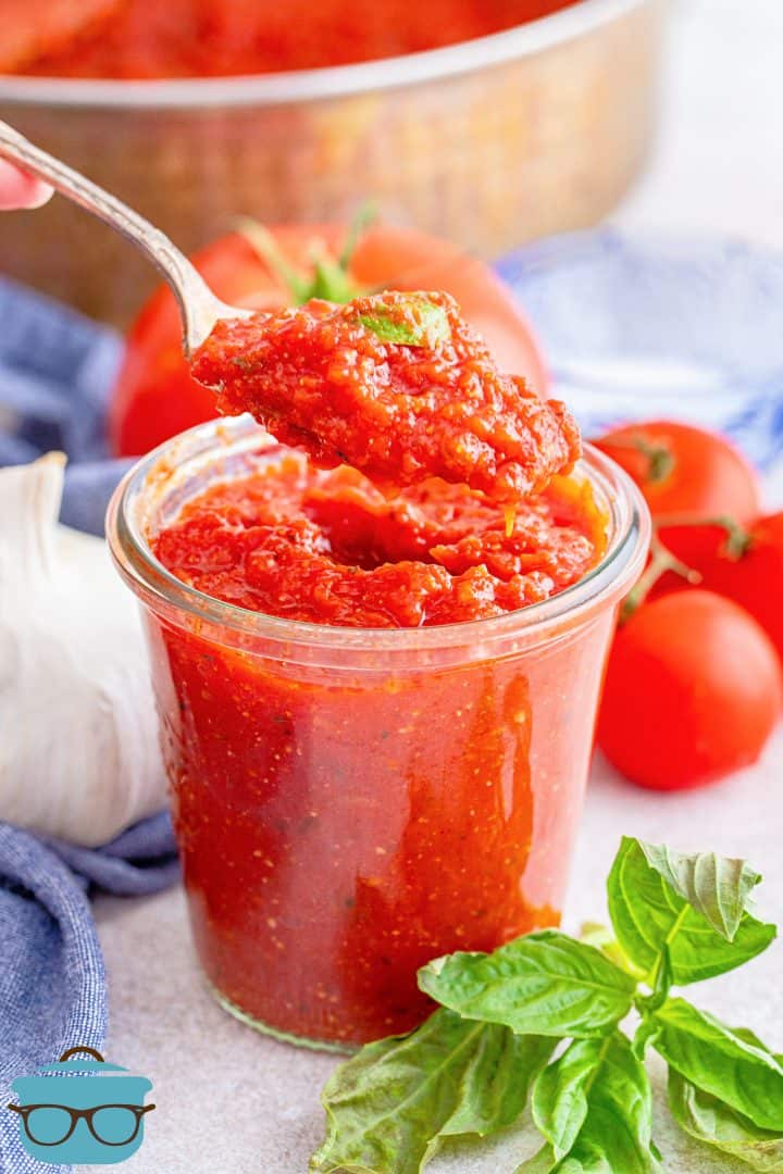 Homemade Pizza Sauce in jar with spoon holding some up.