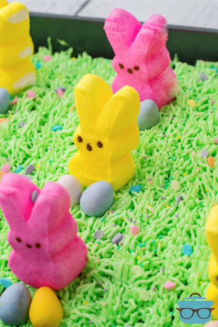 Close up of Easter Bunny Poke Cake topped with grass frosting, peeps and Cadbury eggs.