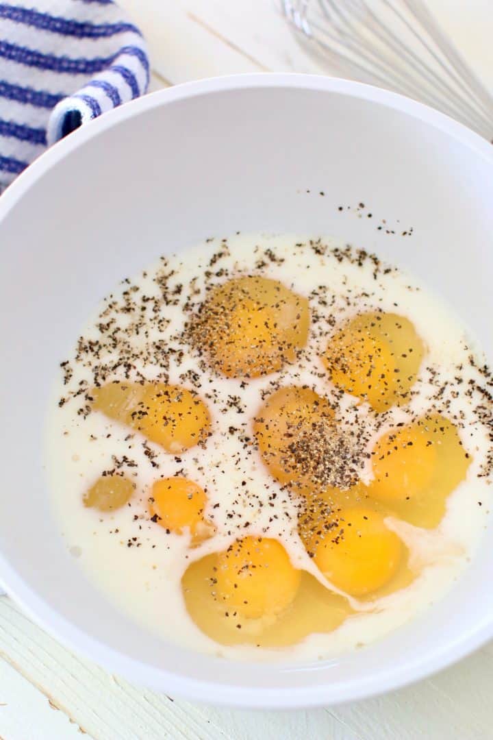 eggs, milk, salt and pepper in a white bowl.