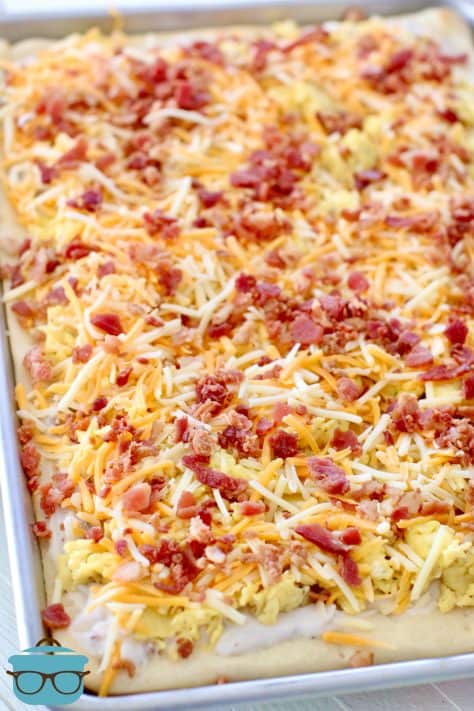 shredded cheese and bacon pieces shown on top of scrambled eggs