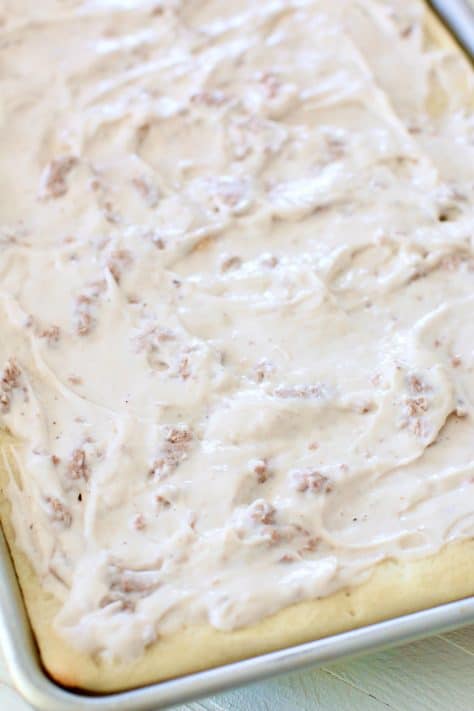 creamy white sausage gravy spread out on pizza crust in baking pan