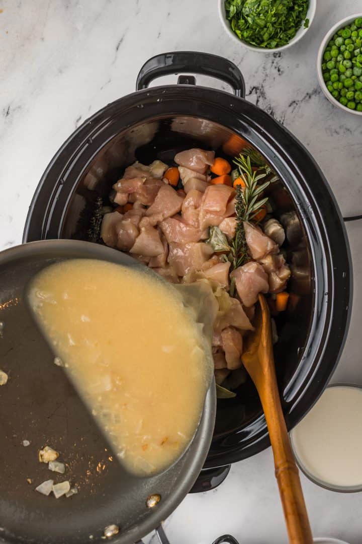 Roux being poured over chicken mixture in crock pot.