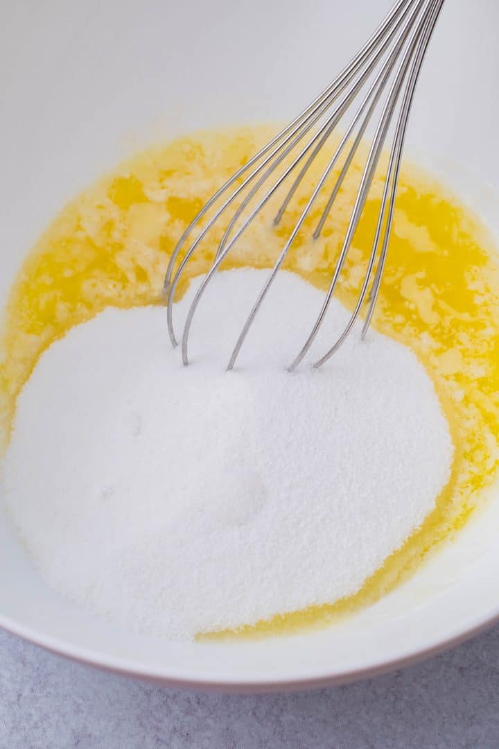 Butter and sugar being whisked in bowl.