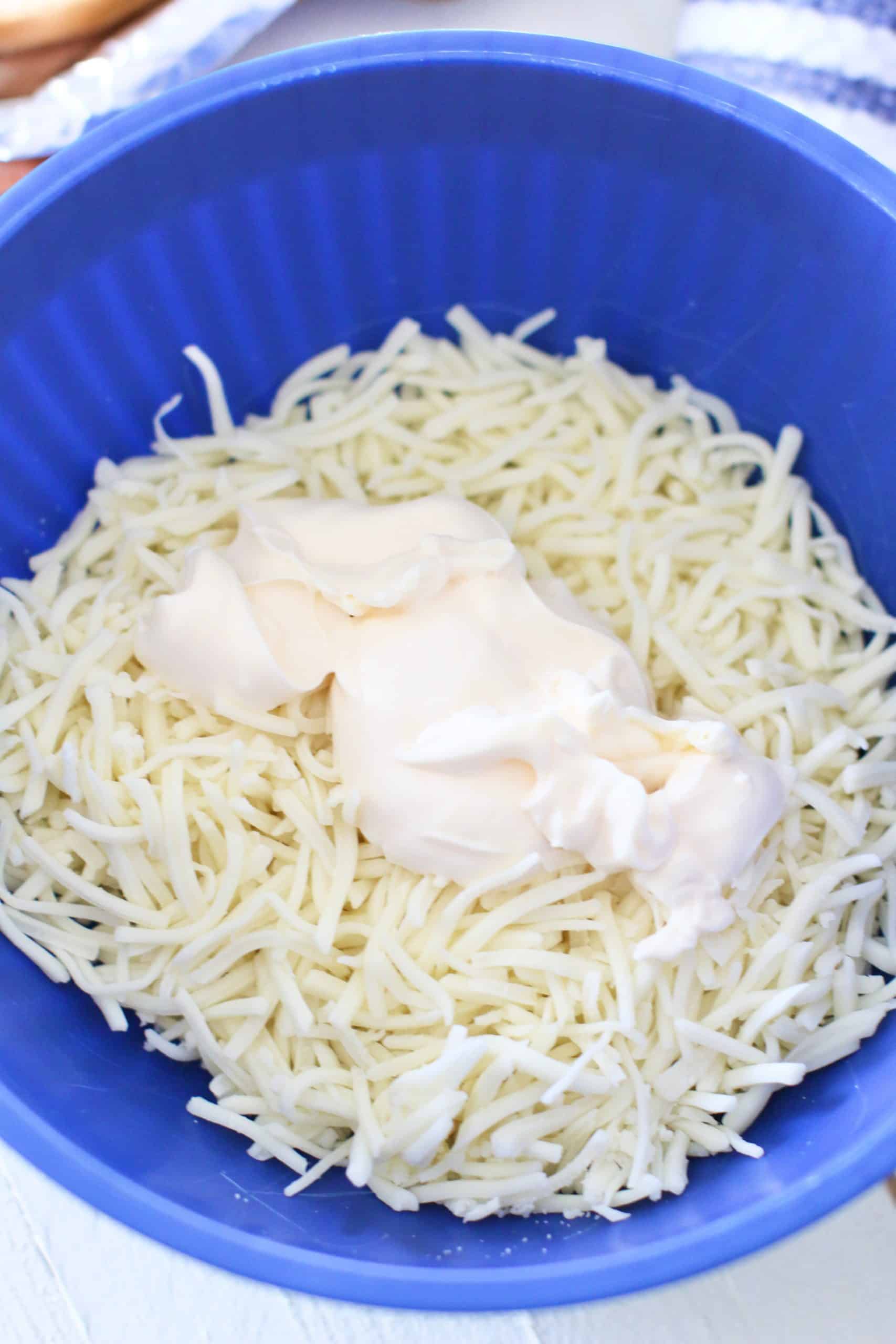 mayonnaise and shredded mozzarella cheese shown in a blue bowl.