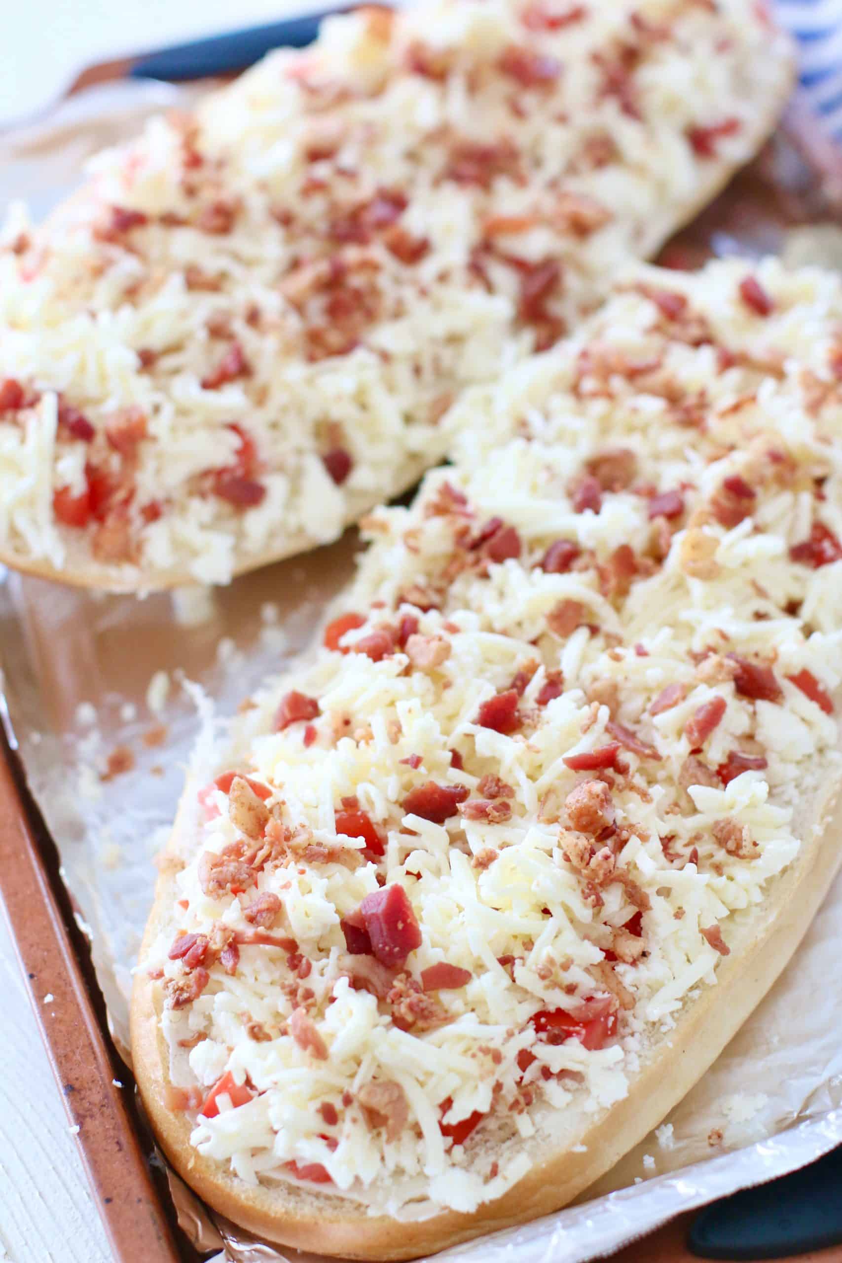 bacon pieces shown on cheese covered Italian bread.