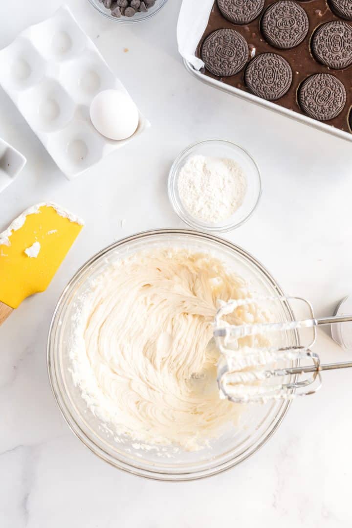 Cream cheese mixture beaten together with an electric mixer shown off to the side of the bowl.