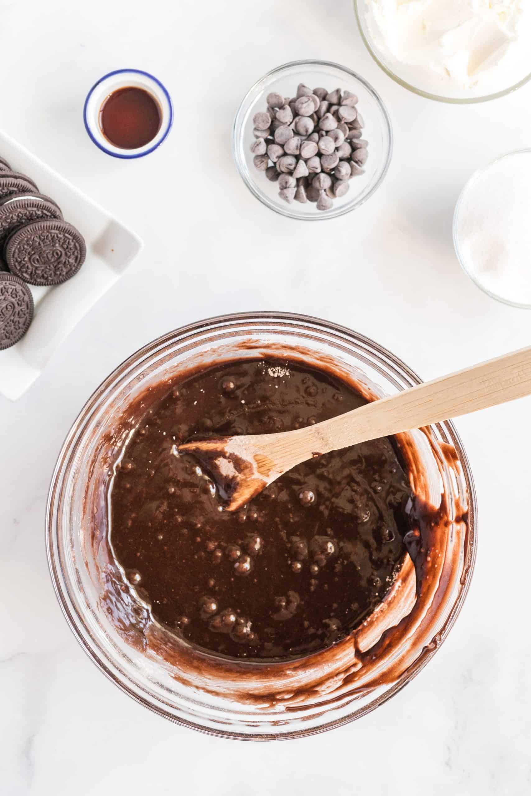 Mixed up brownie mix in bowl in a clear bowl with a wooden spoon.