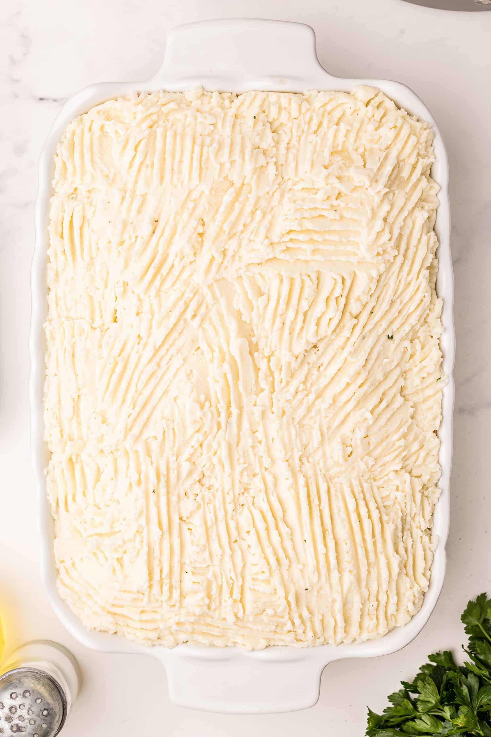 meat mixture in casserole dish fully covered by a layer of mashed potatoes.