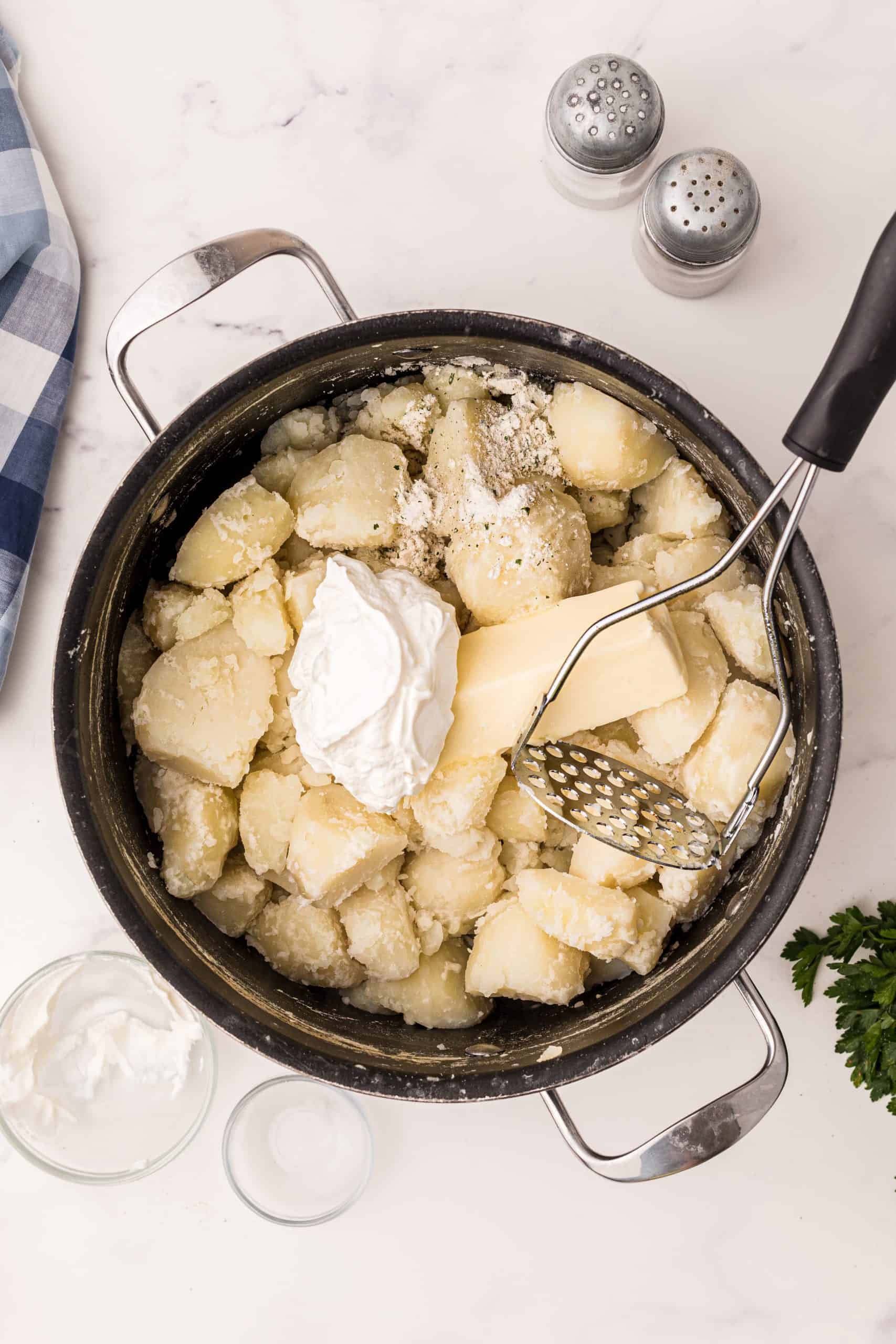 Sour cream, butter and ranch seasoning added to cooked potatoes in a large pot.