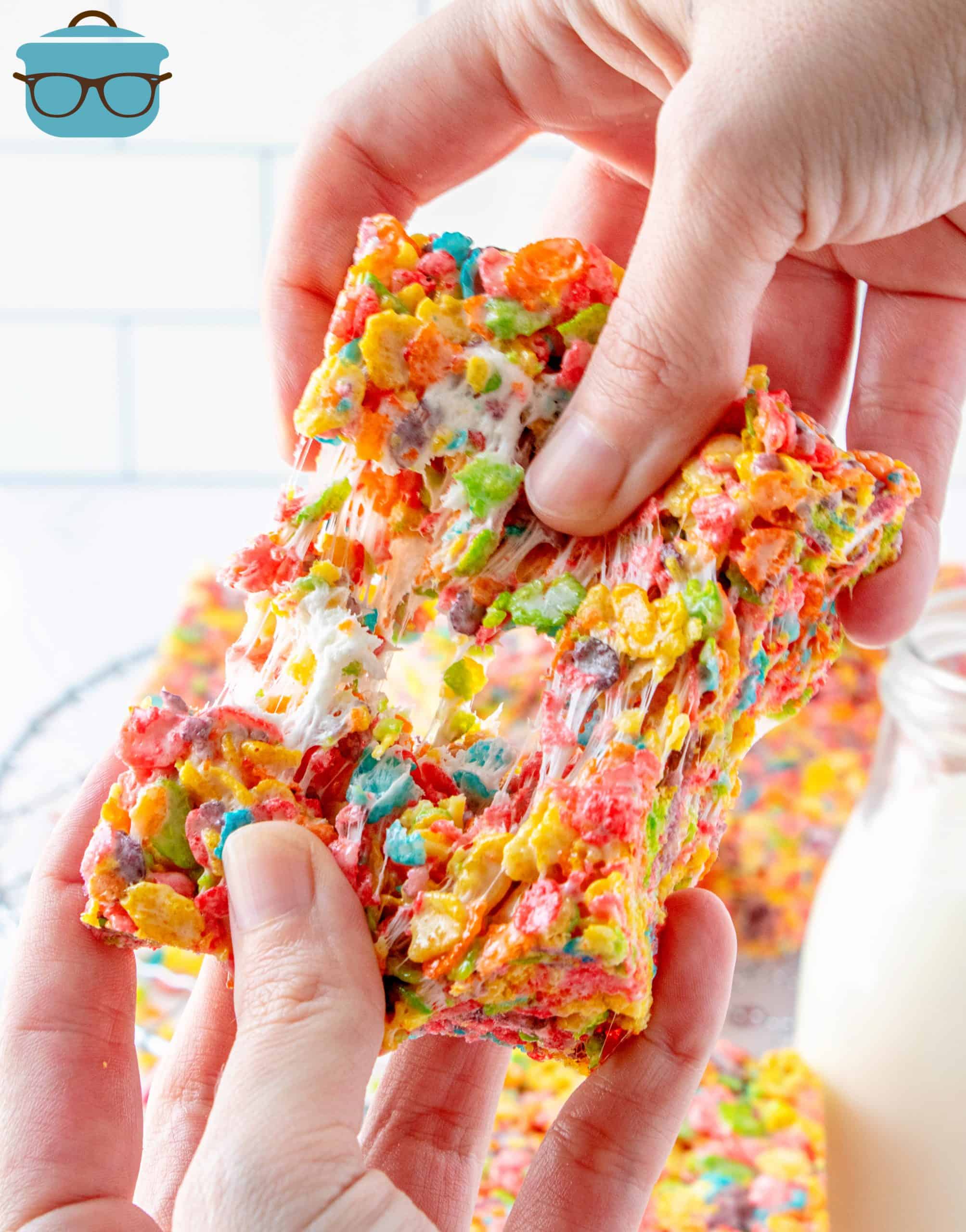 Hand pulling apart one Fruity Pebbles Treat.
