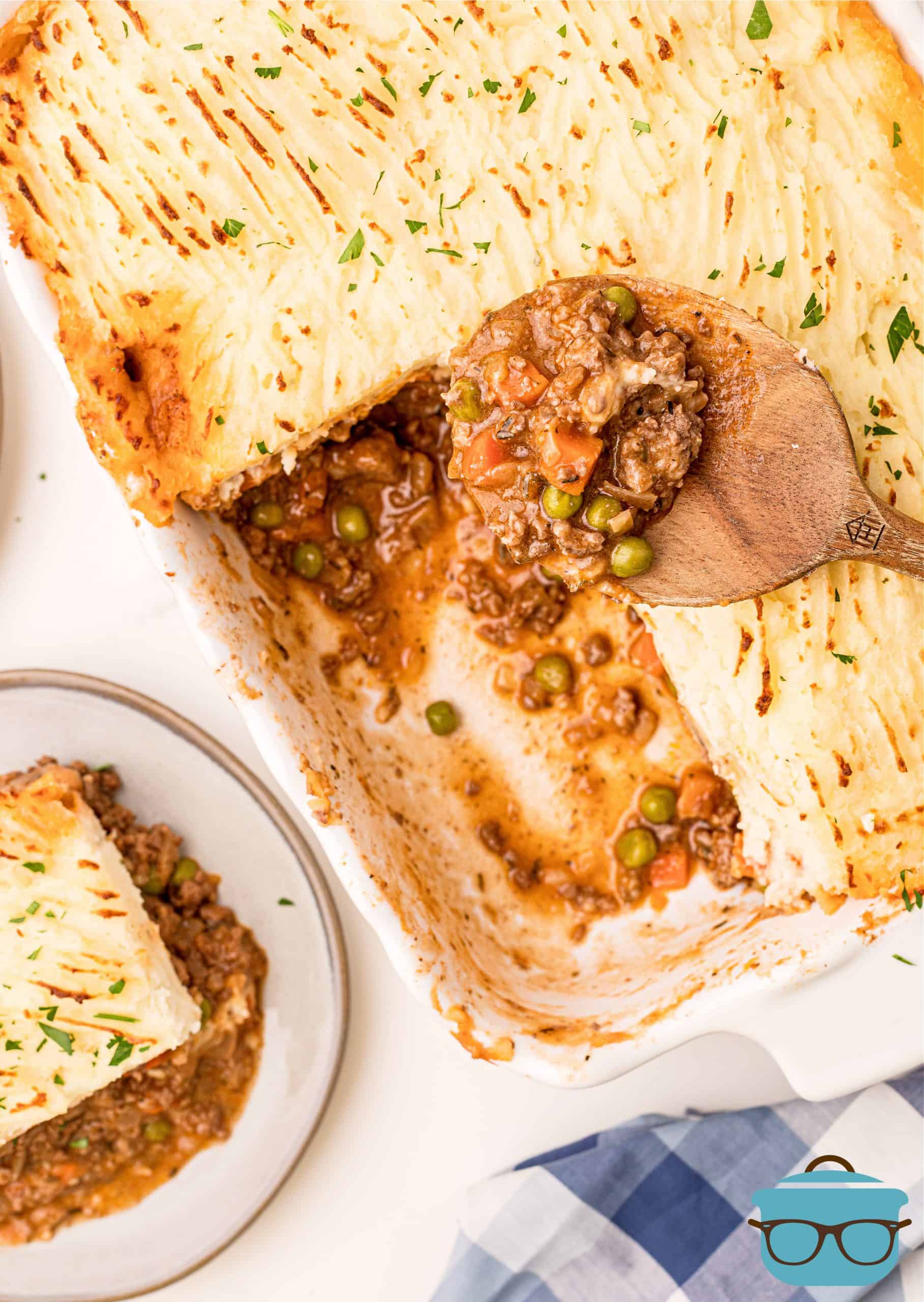 Overhead photo of slice of Shepherd's Pie on plate with some removed from casserole dish.