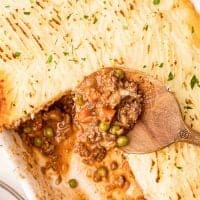 Close up of Shepherd's Pie in pan with serving spoon with some missing square image
