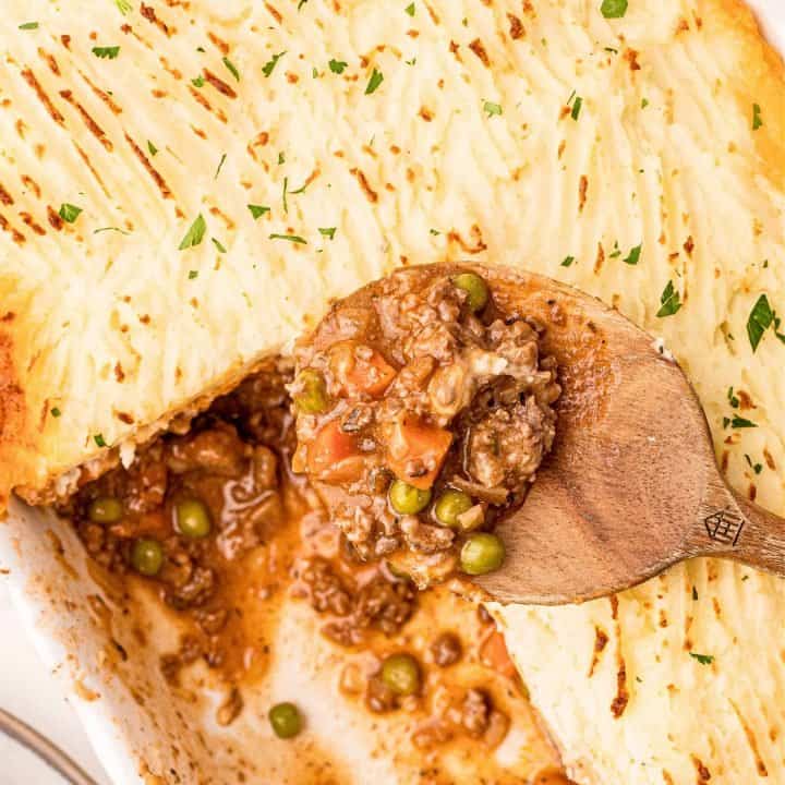 Close up of Shepherd's Pie in pan with serving spoon with some missing square image