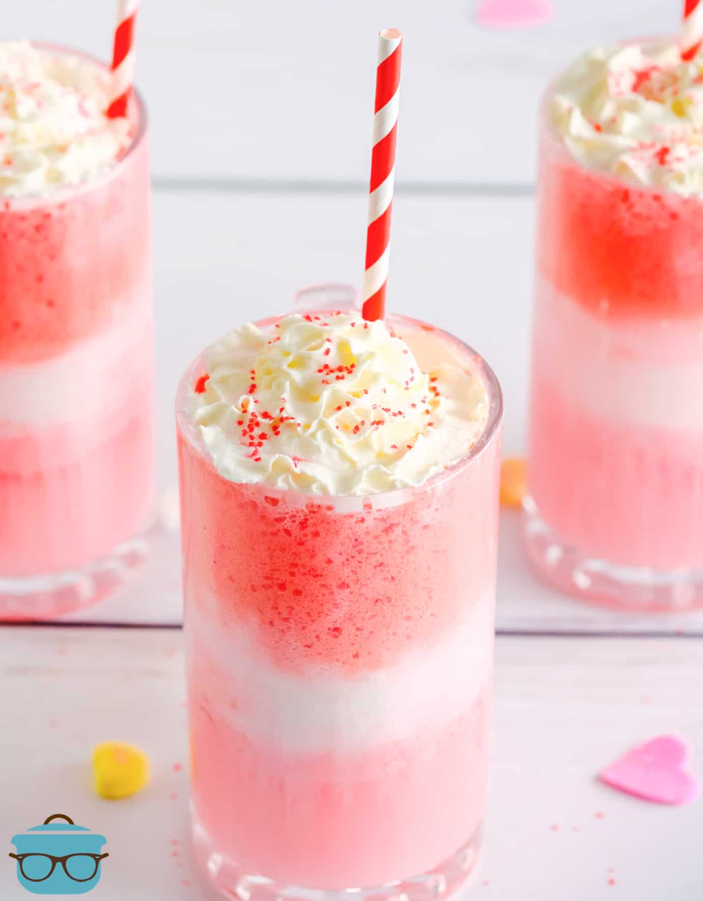 Close up of Strawberry Cream Floats in glass topped with whipped cream, sprinkles and a straw.