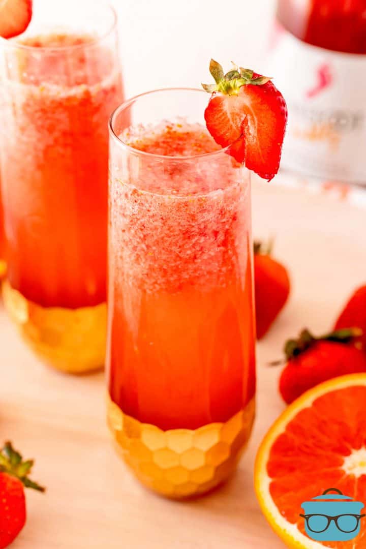 Close up of Strawberry Mimosas in two glasses garnished with strawberries.