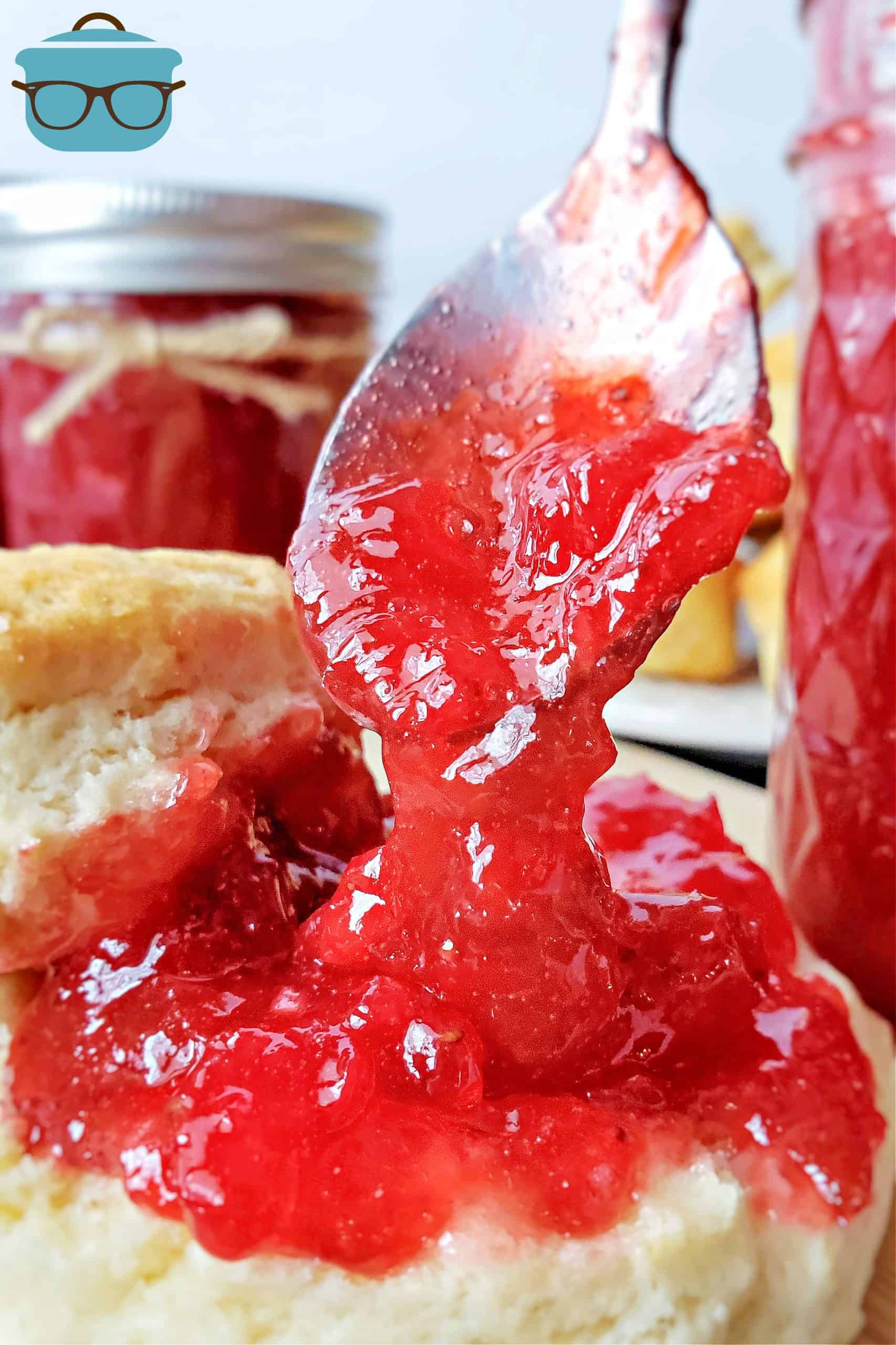 Strawberry Rhubarb Jam being spooned over a biscuit.