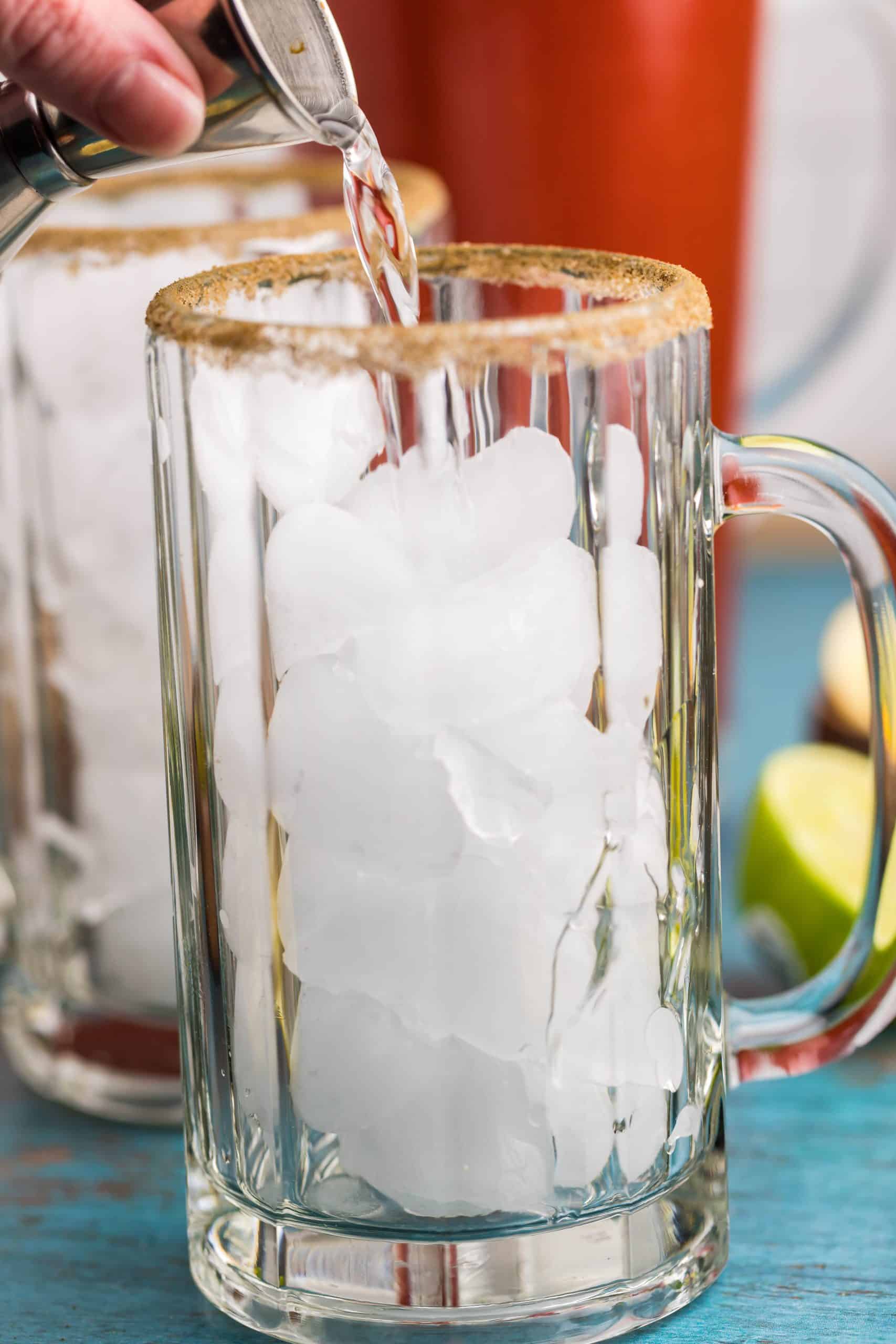 Glasses with ice and vodka being poured into them.
