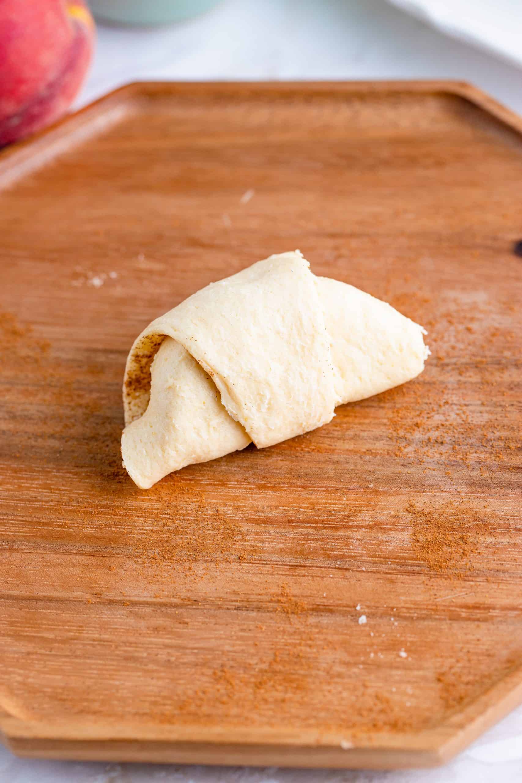 Peach rolled up in crescent roll making a dumpling.