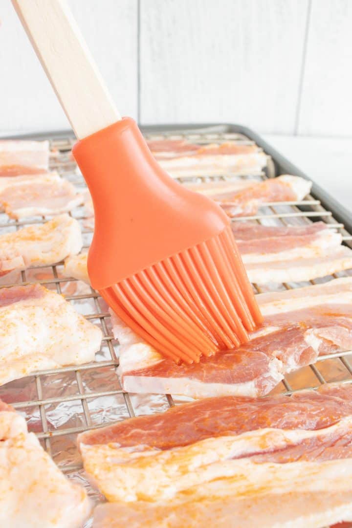 Basting brush brushing cut bacon with hot sauce.