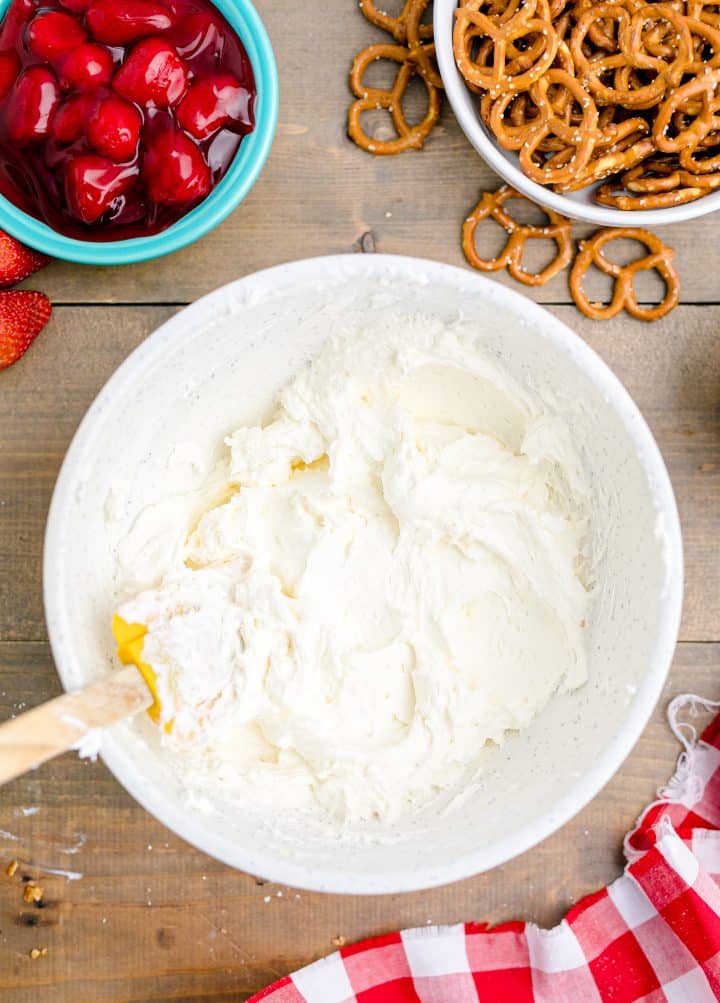 Whipped topping being folded into cream cheese mixture in white bowl overhead photo.