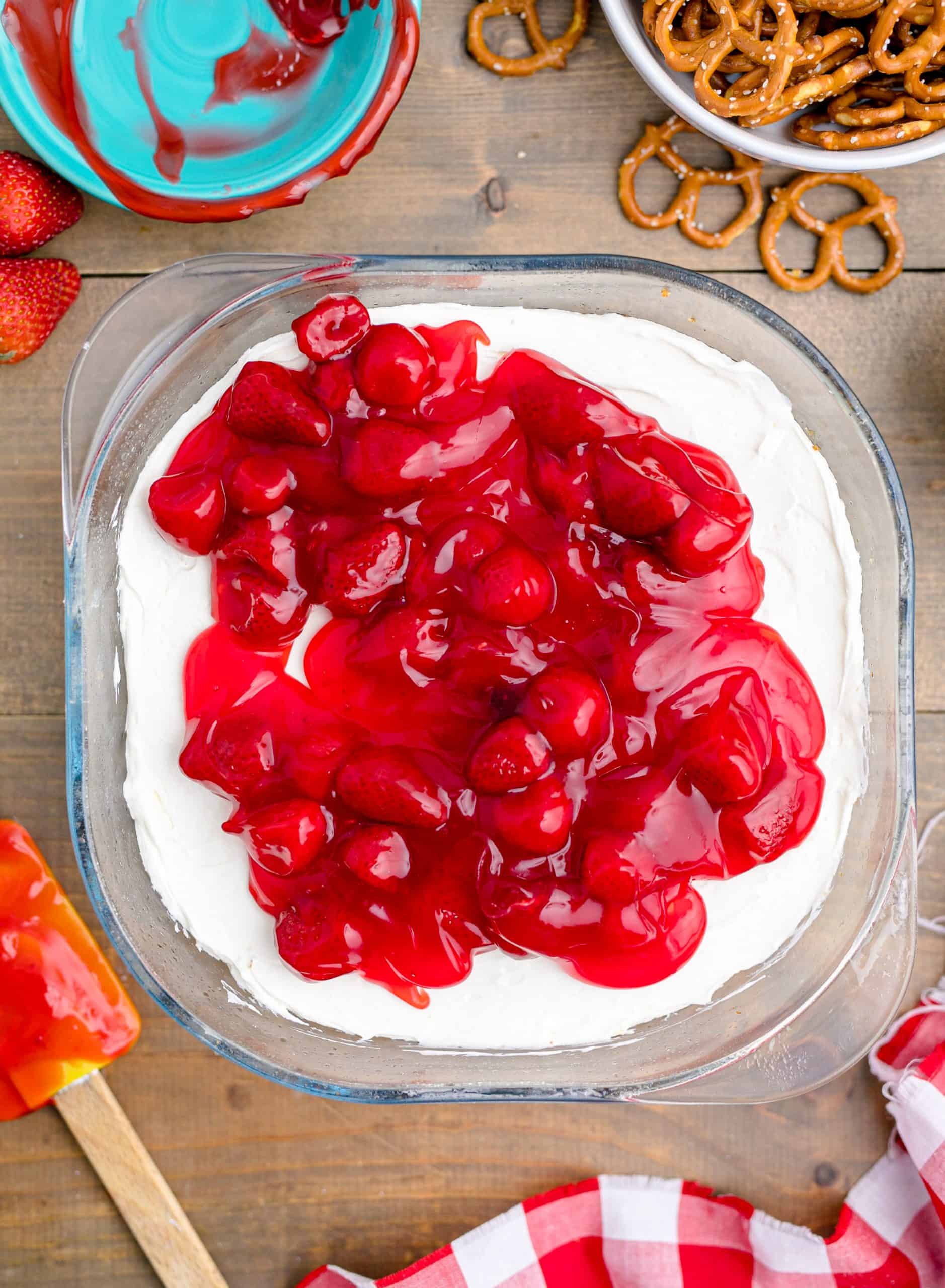 Strawberries added on top of cream cheese mixture in baking dish.